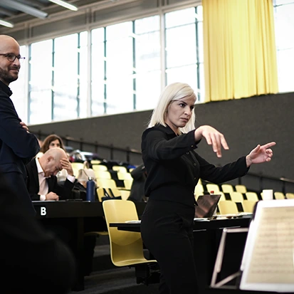 Femme chef d’orchestre levant la baguette avec énergie — Atelier Maestro for a Day avec Guillaume berney _ switerland